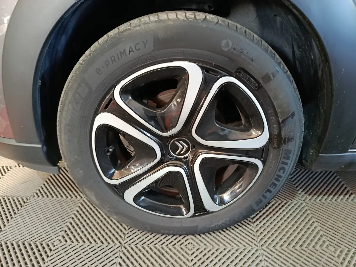 Gros plan sur la roue avant droite d’une Citroën C3 gris foncé, jante alliage noire et argent avec logo Citroën central.