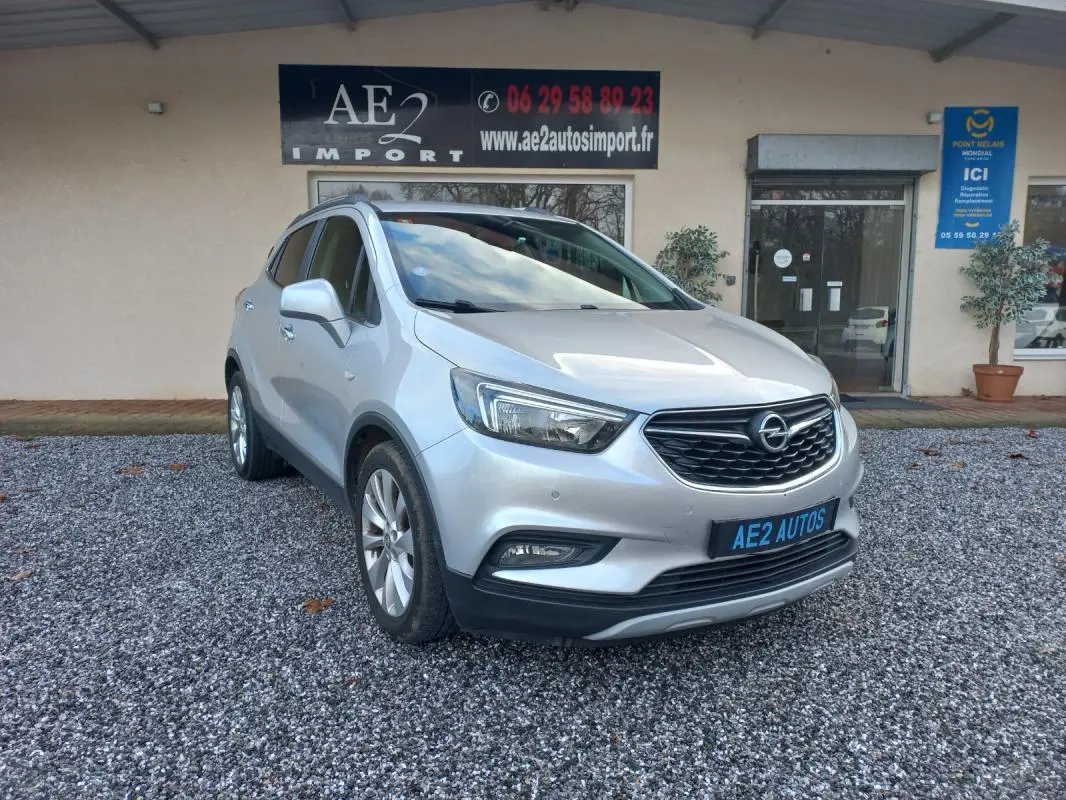 Opel Mokka X gris 2017 en 3/4 avant droit, avec calandre noire et jantes alliage visibles.