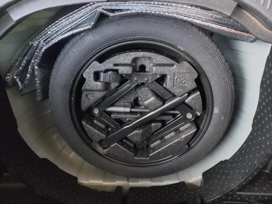 Roue de secours avec outillage intégré dans le coffre d'un Opel Mokka X gris 2017, vue en plongée.