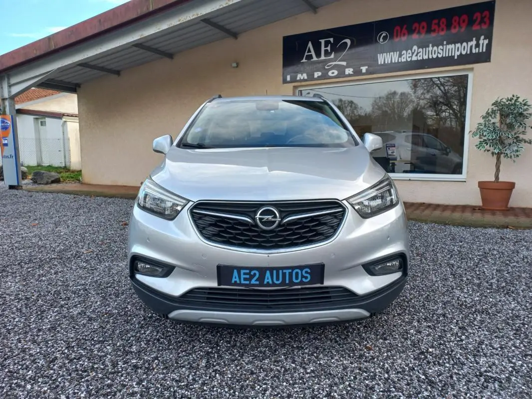 Vue avant d'un Opel Mokka X gris 2017, avec calandre noire et plaque AE2 AUTOS visible.
