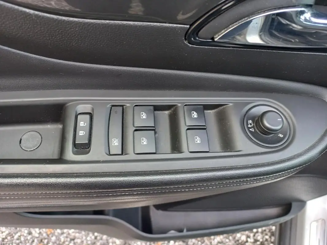 Gros plan sur les commandes des vitres et rétroviseurs côté conducteur d’un Opel Mokka X gris, intérieur noir.
