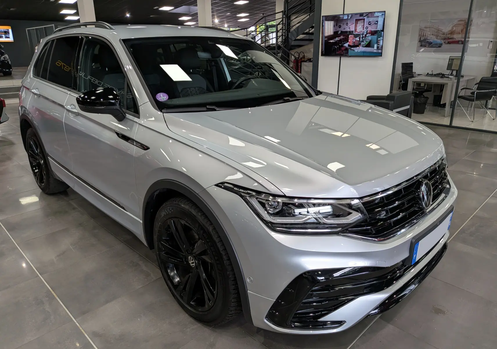 Volkswagen Tiguan 1.5 TSI R-Line reflet d'argent, vue 3/4 avant droit avec jantes noires et calandre sportive.