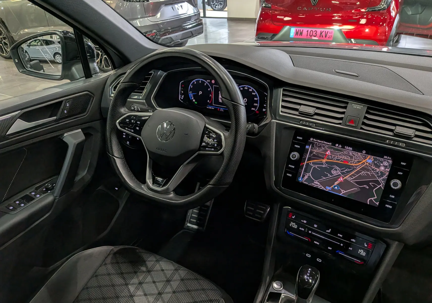 Vue intérieure côté conducteur du Volkswagen Tiguan 2024, tableau de bord noir avec écran tactile et volant multifonction.