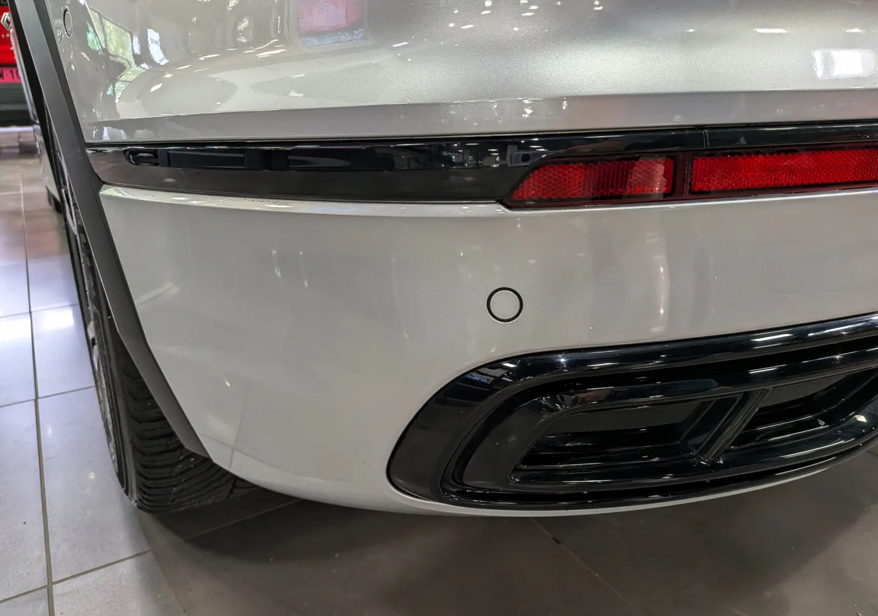 Gros plan sur le coin arrière droit du Volkswagen Tiguan 2024 reflet d'argent, avec feu arrière et sortie d'échappement noire.