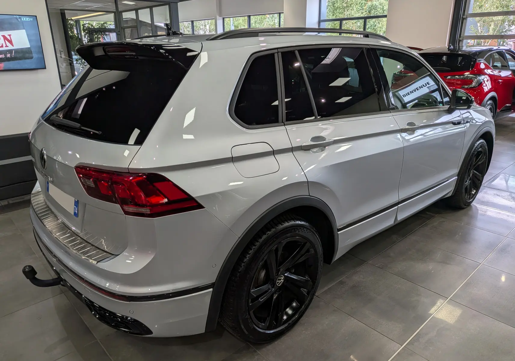 Volkswagen Tiguan 2024 reflet d'argent en vue 3/4 arrière droit, jantes noires et vitres teintées en showroom.