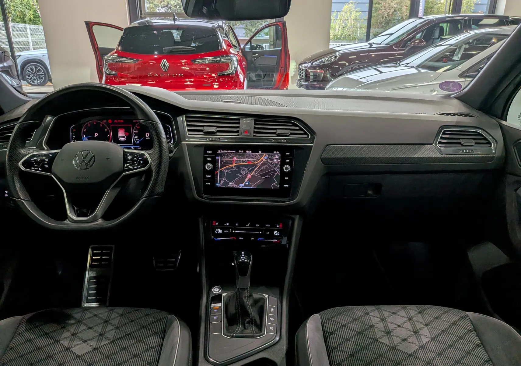 Vue intérieure avant du Volkswagen Tiguan 2024 en reflet d'argent, avec tableau de bord numérique et écran tactile central allumé.