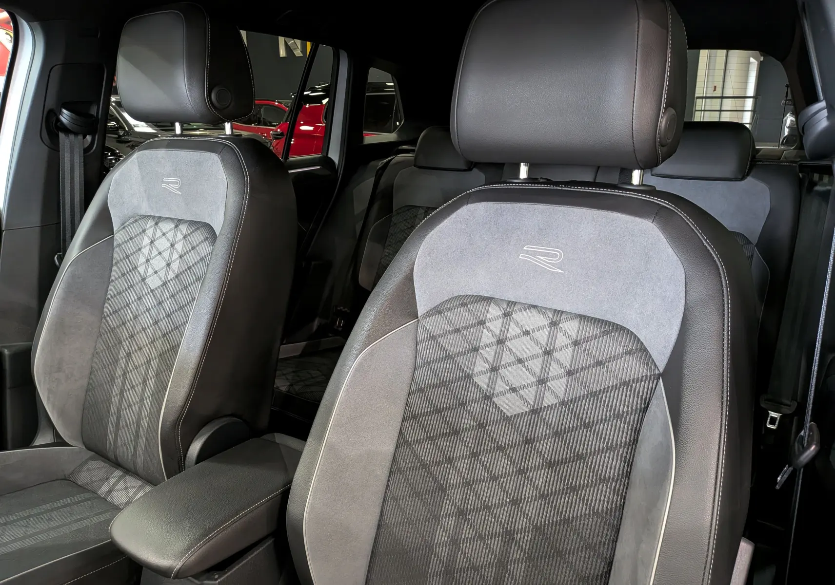 Gros plan sur les sièges avant en cuir gris et alcantara avec logo R du Volkswagen Tiguan 2024, ambiance intérieure raffinée.