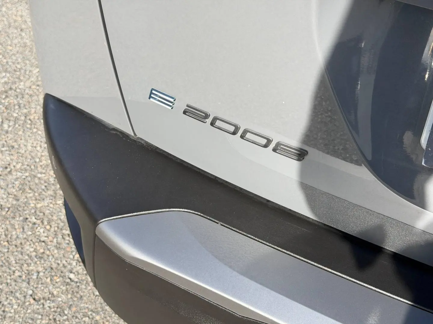 Détail du logo e-2008 sur le coffre arrière gris Artense avec pare-chocs noir, vue en gros plan côté droit.