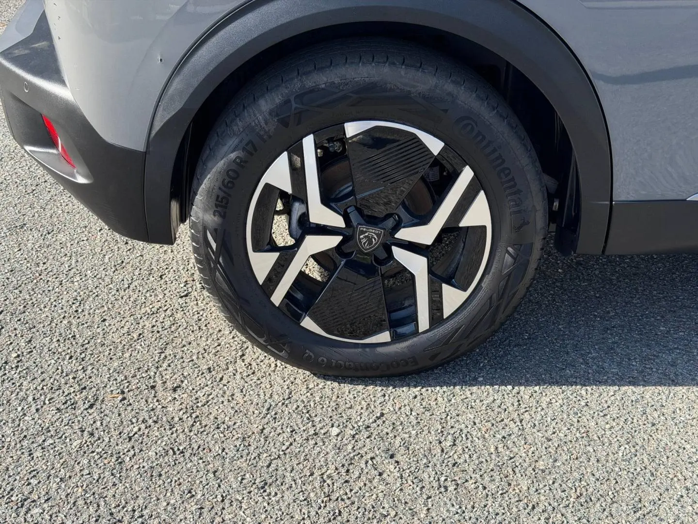 Gros plan sur la roue arrière droite avec jante alu bicolore du Peugeot e-2008 gris Artense 2025.