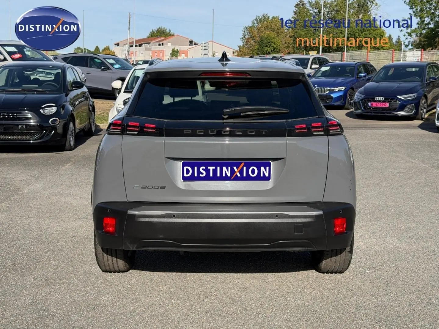 Vue arrière d'un Peugeot e-2008 gris Artense 2025 avec feux LED et lunette arrière surteintée sur parking.