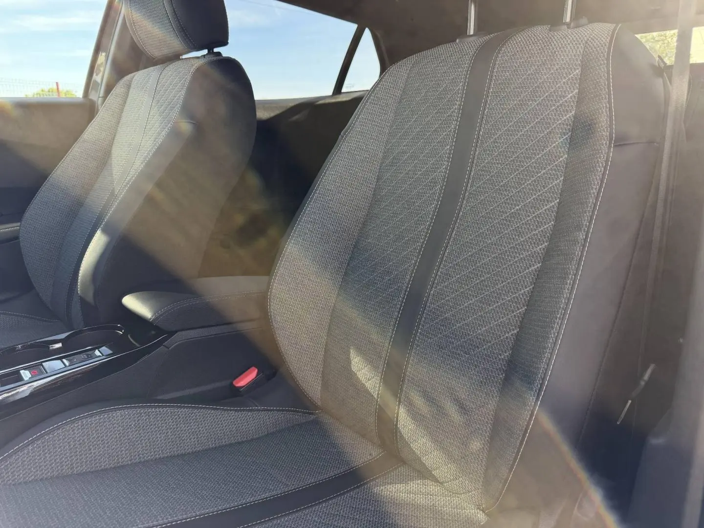 Gros plan sur les sièges avant gris tissu CASUAL LOMSA embossé de la Peugeot e-2008 2025, lumière naturelle traversante.