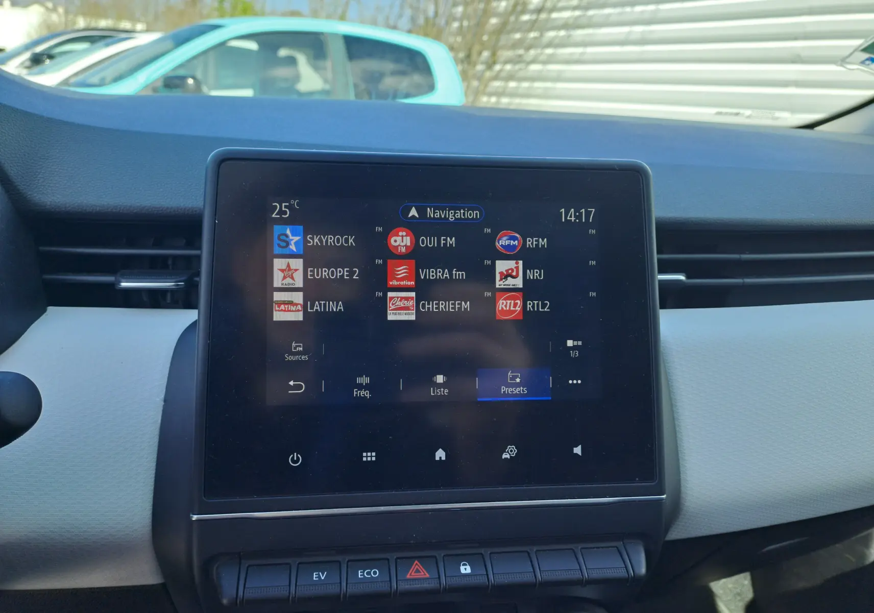 Vue intérieure du tableau de bord de la Renault Clio V gris Highland Metal, écran tactile affichant les stations radio.