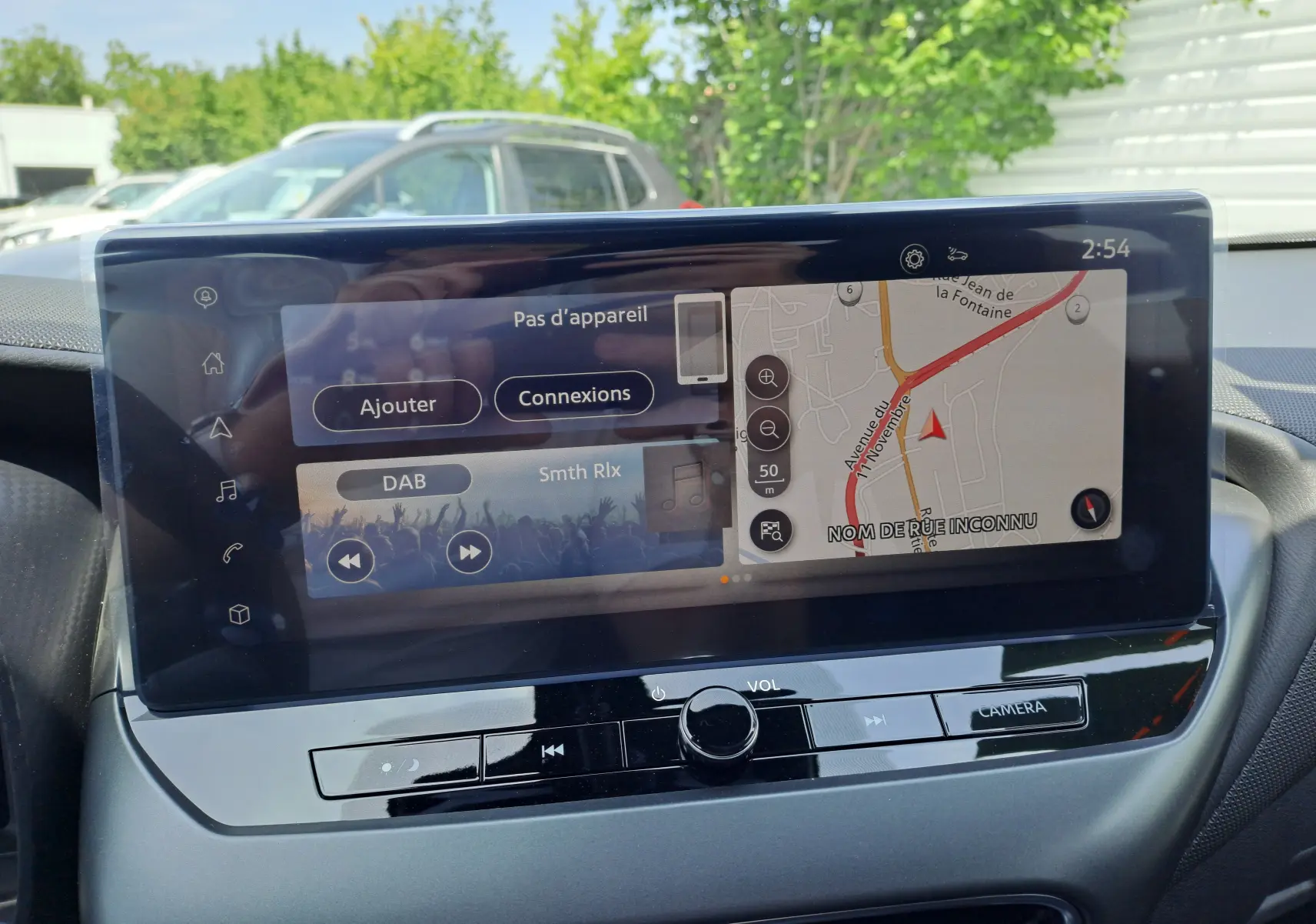 Écran tactile central du Nissan Juke Hybrid 2025 affichant navigation et radio DAB, avec commandes volume et caméra visibles.