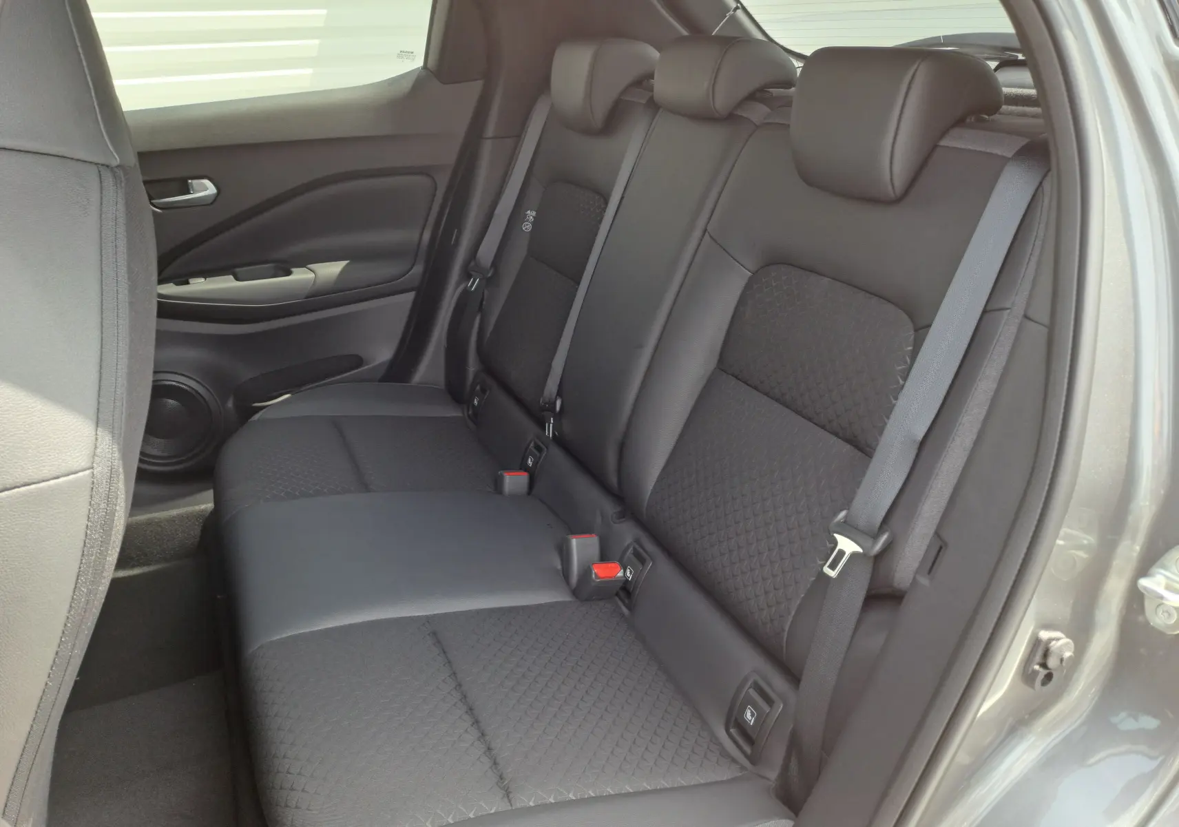 Vue intérieure côté droit des sièges arrière noirs en tissu et cuir du Nissan Juke Hybrid 143 N-Connecta gris squale 2025.