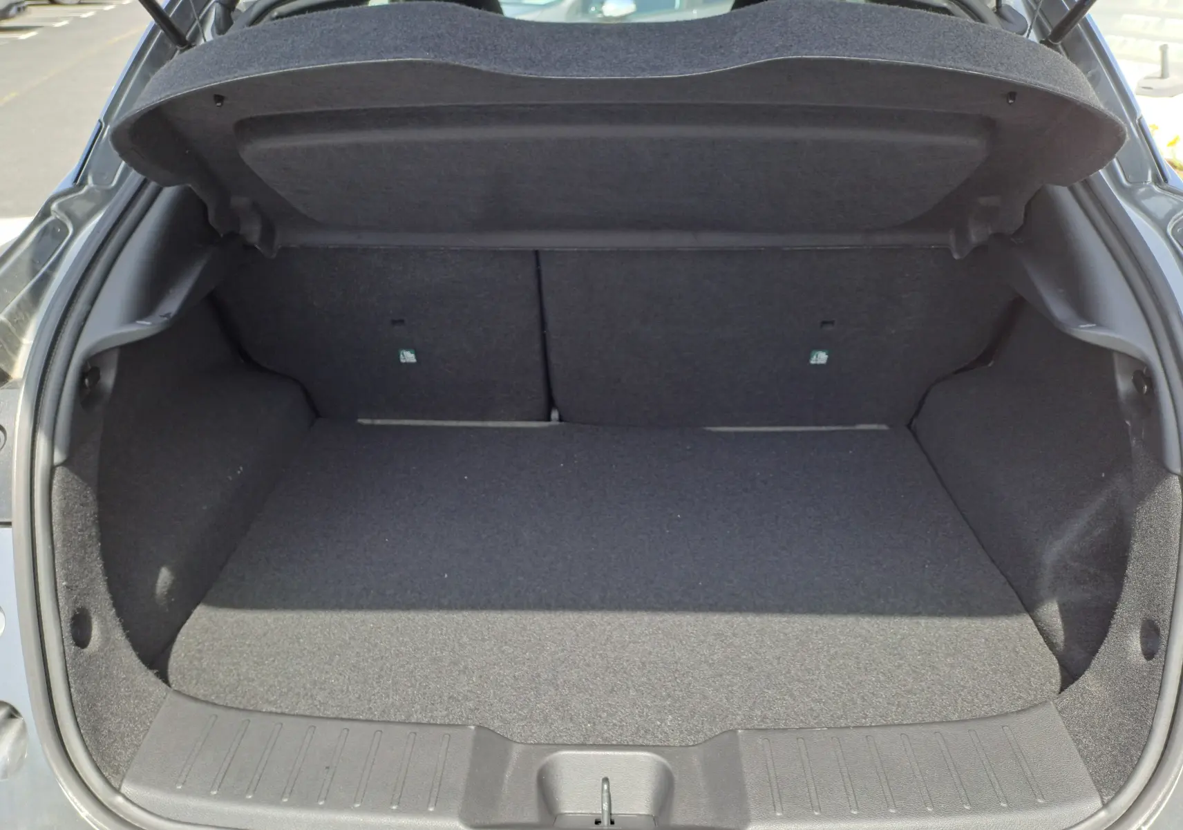 Coffre ouvert du Nissan Juke Hybrid 143 N-Connecta gris squale, vue intérieure arrière montrant l'espace de chargement vide.