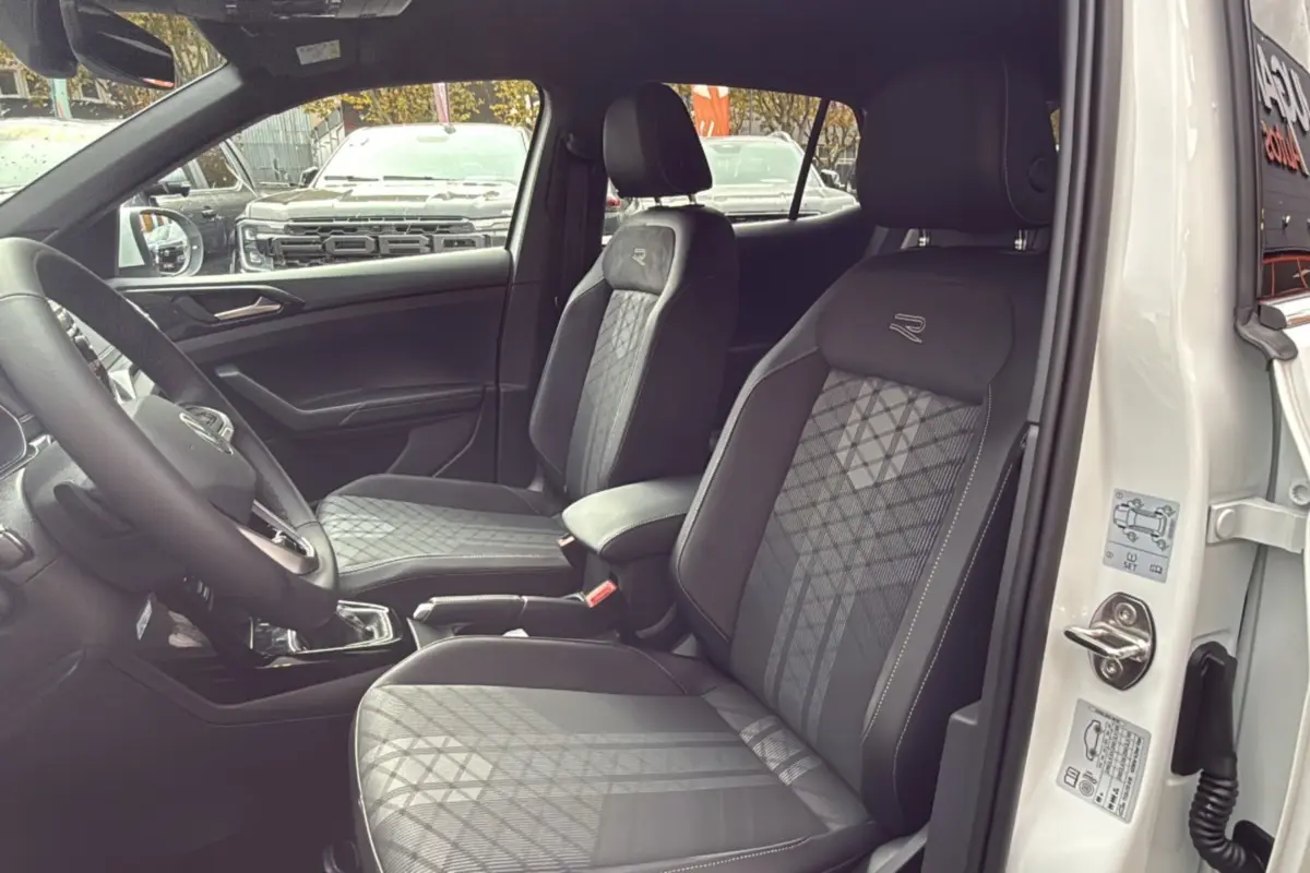 Intérieur du Volkswagen T-Cross TSI 116 DSG7 R-Line blanc, vue côté conducteur sur les sièges avant en tissu avec logo R.