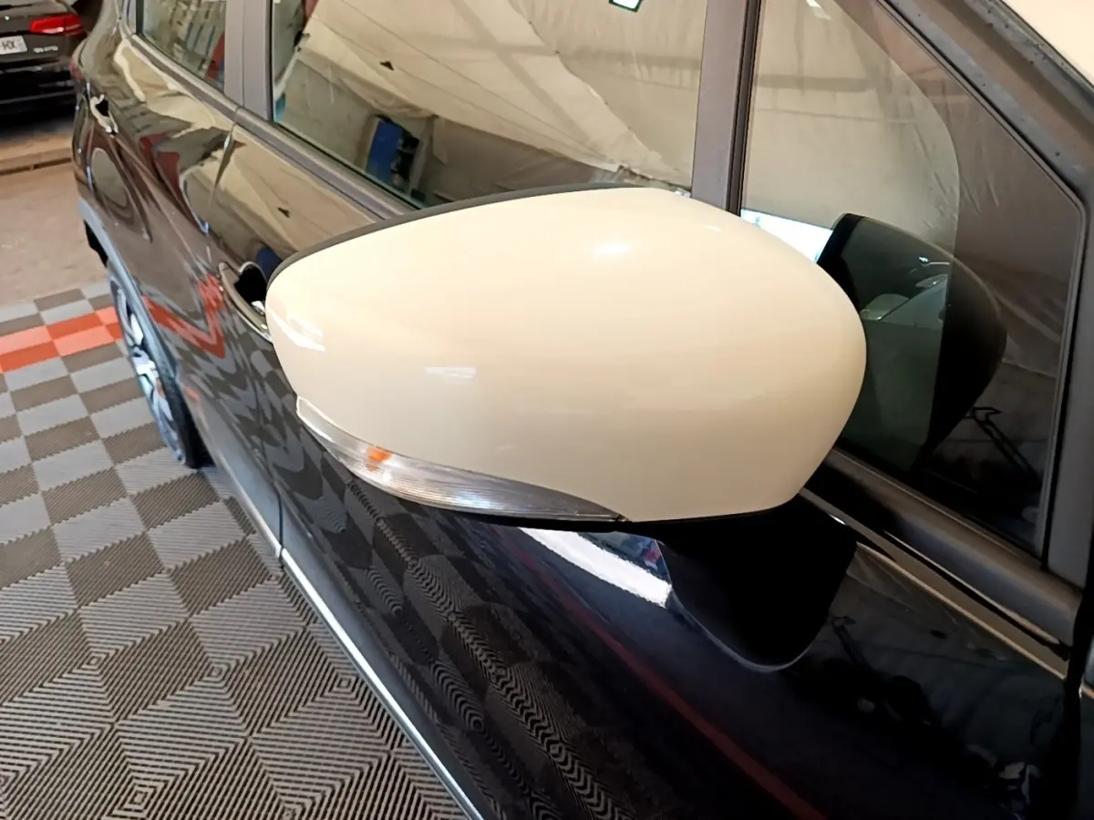 Rétroviseur blanc en gros plan côté gauche d’un Renault Captur noir, reflet de l’environnement intérieur visible.