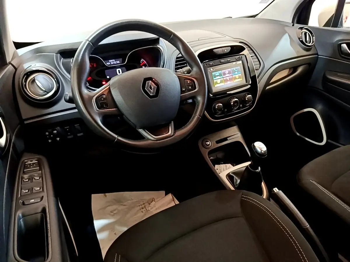Vue intérieure côté conducteur du tableau de bord noir du Renault Captur avec volant cuir et écran tactile central.