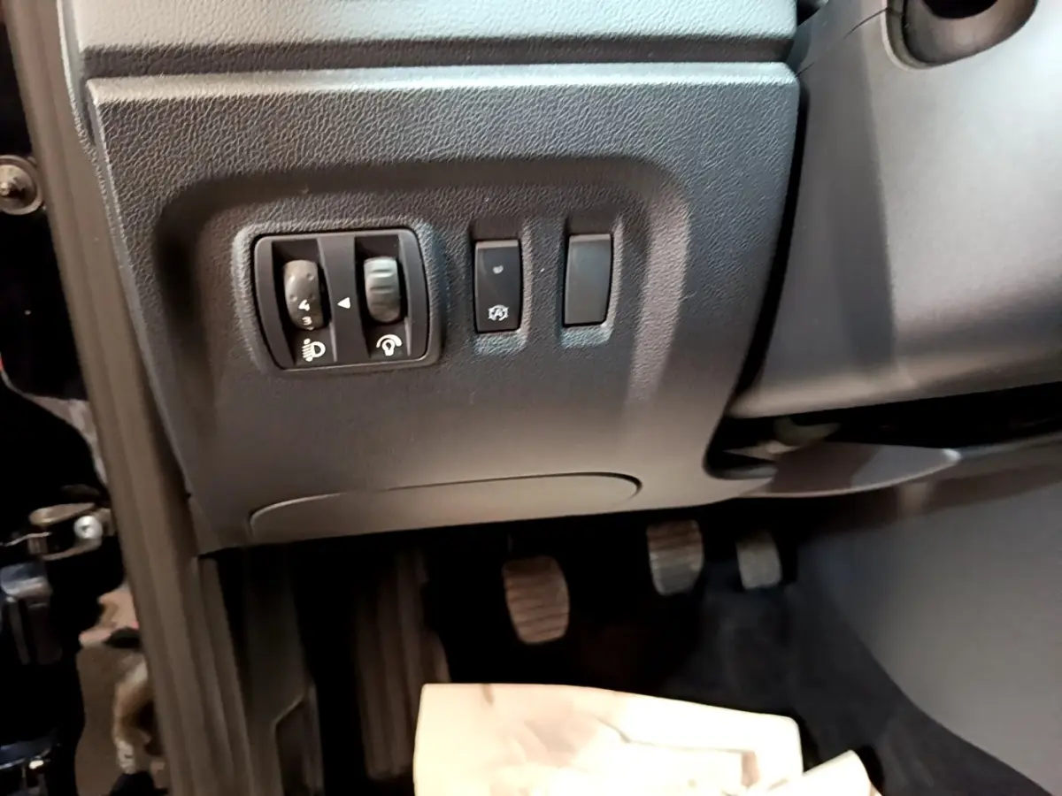 Gros plan sur les commandes de réglage des phares et autres boutons à gauche du volant dans le Renault Captur Business noir 2018.