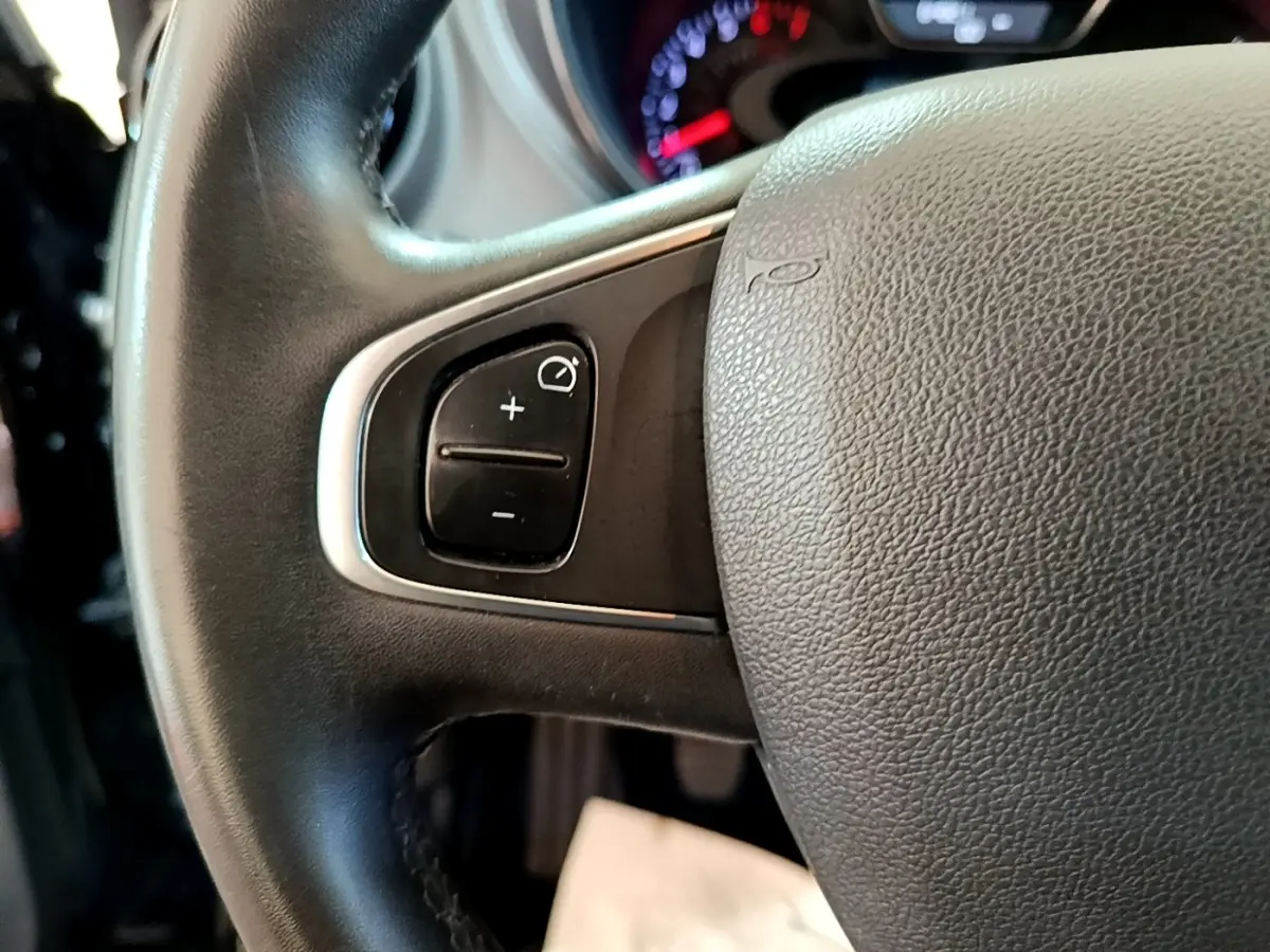 Gros plan sur le volant cuir noir du Renault Captur Business TCe 90, avec commandes de régulateur de vitesse visibles.