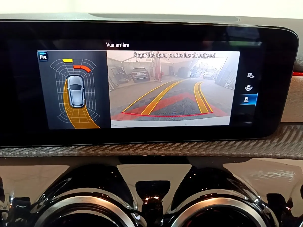 Écran tactile intérieur montrant la caméra de recul et l’aide au stationnement de la Mercedes Classe A blanche.