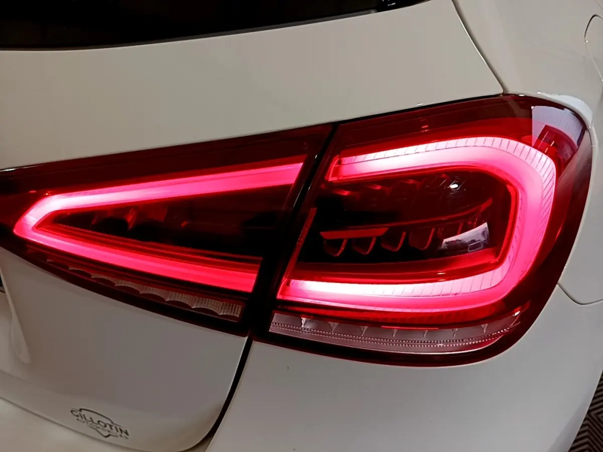Gros plan sur le feu arrière droit rouge vif d’une Mercedes Classe A Berline blanche, version hybride rechargeable.