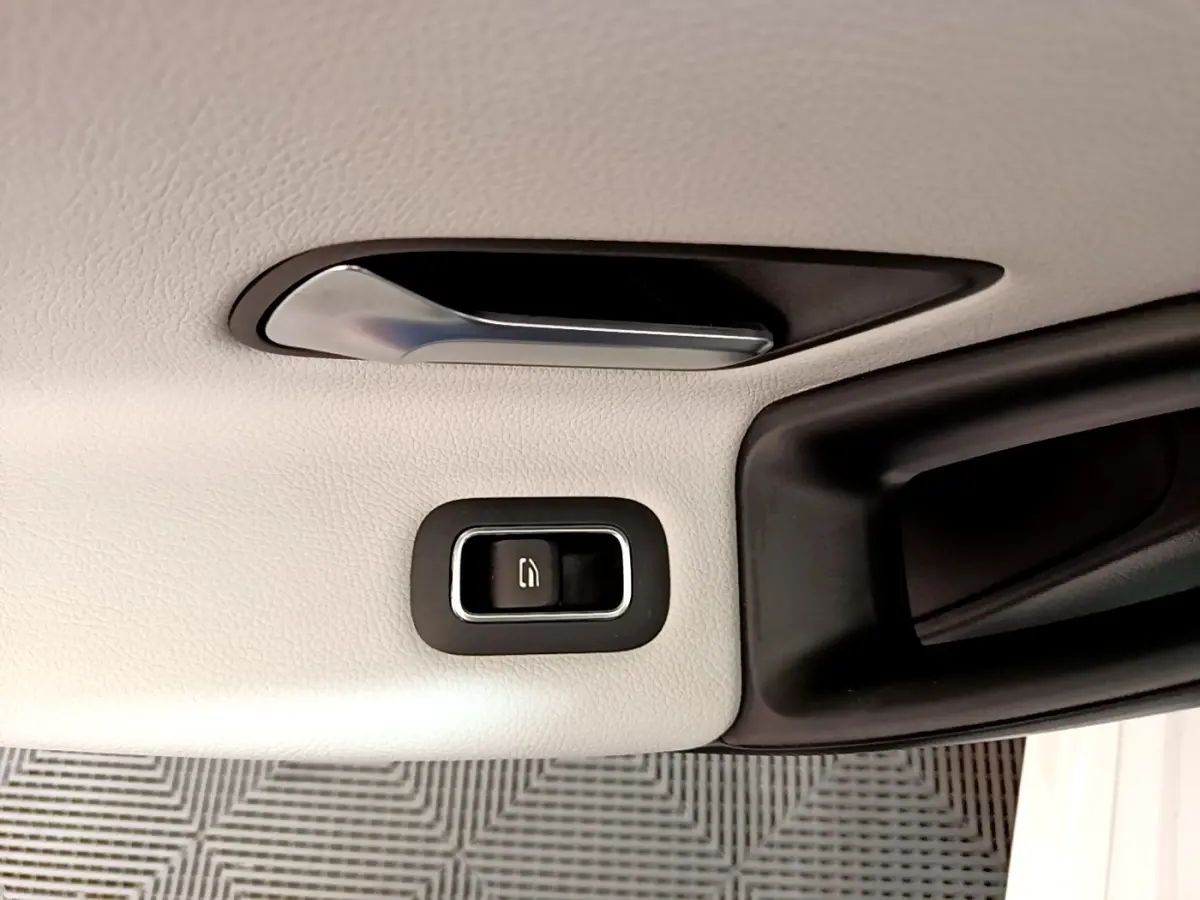 Gros plan sur la poignée intérieure et le bouton de verrouillage de porte, garniture cuir blanc de la Mercedes Classe A.