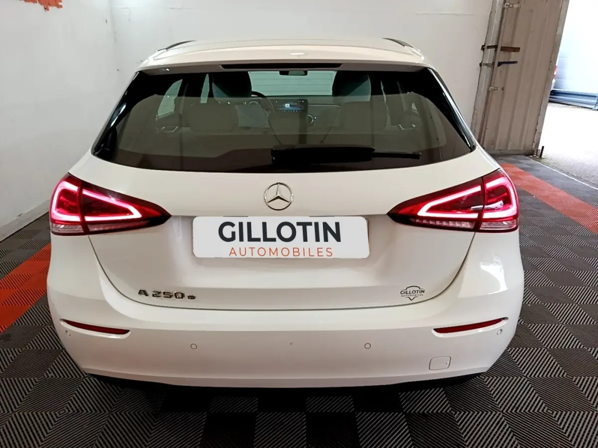 Vue arrière d'une Mercedes Classe A 250 e Business Line blanche avec feux LED allumés dans un garage.