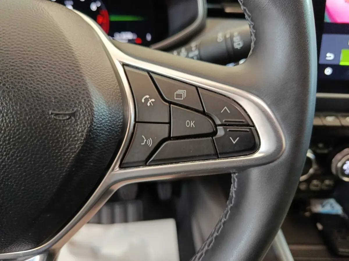 Gros plan sur les commandes multifonctions à droite du volant noir de la Renault Clio Techno TCe 90 rouge 2024.