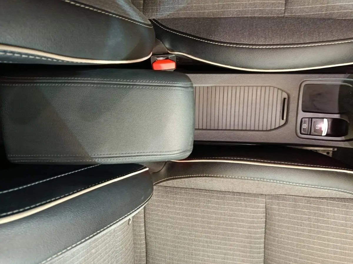 Vue plongeante sur la console centrale noire et les sièges gris foncé avec surpiqûres blanches de la Renault Clio 2024.