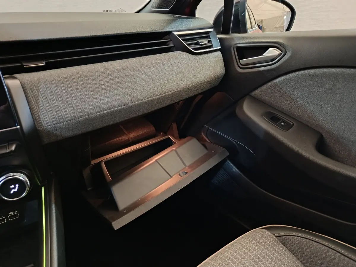 Intérieur de la Renault Clio Techno TCe 90 2024, vue côté passager avec boîte à gants ouverte et tissus gris.