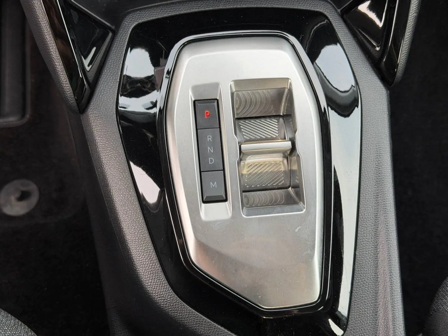 Gros plan sur la console centrale noire et argentée de la Peugeot 208 Hybrid, avec levier de vitesses automatique.