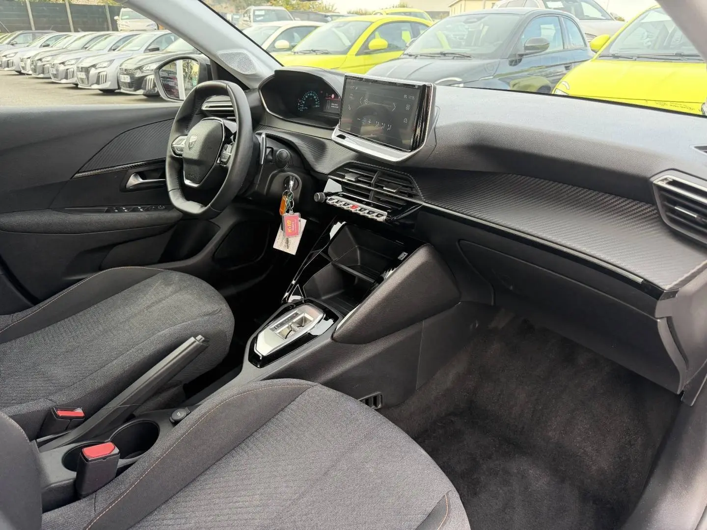 Vue intérieure côté conducteur de la Peugeot 208 1.2 Hybrid 110ch Style 2025 avec tableau de bord moderne et sièges tissu gris.