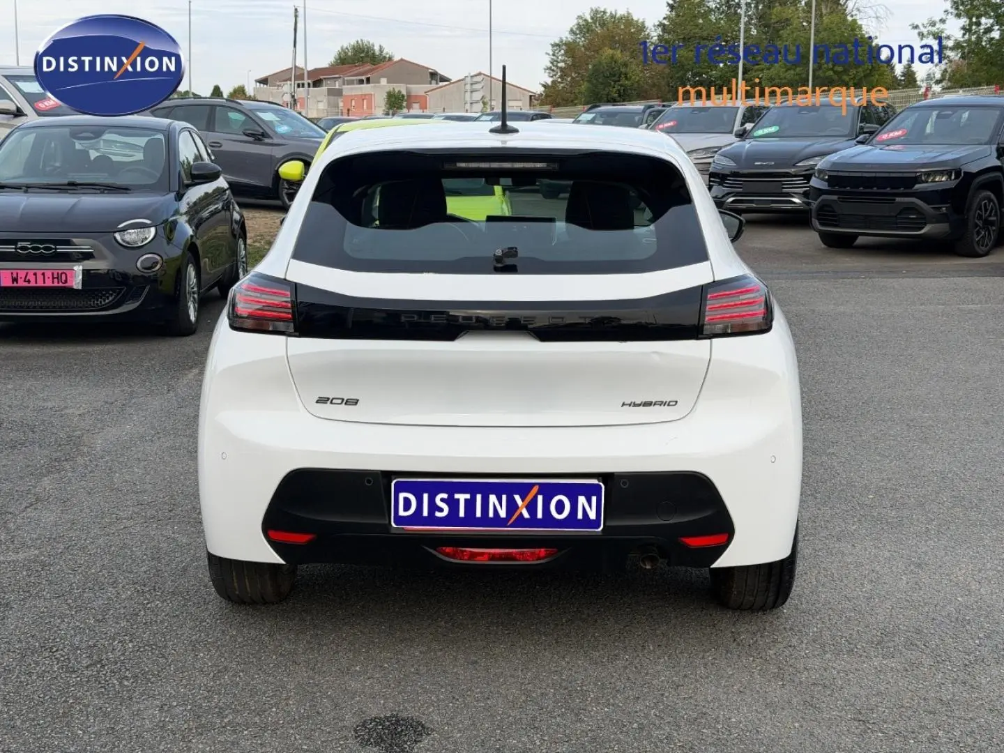 Vue arrière d'une Peugeot 208 blanche Okénite avec logo noir brillant et feux arrière LED horizontaux.
