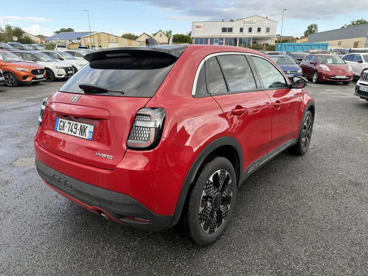 Vue 3/4 arrière droite d'une FIAT 600 hybride rouge avec jantes alliage 18'' et vitres arrière surteintées.