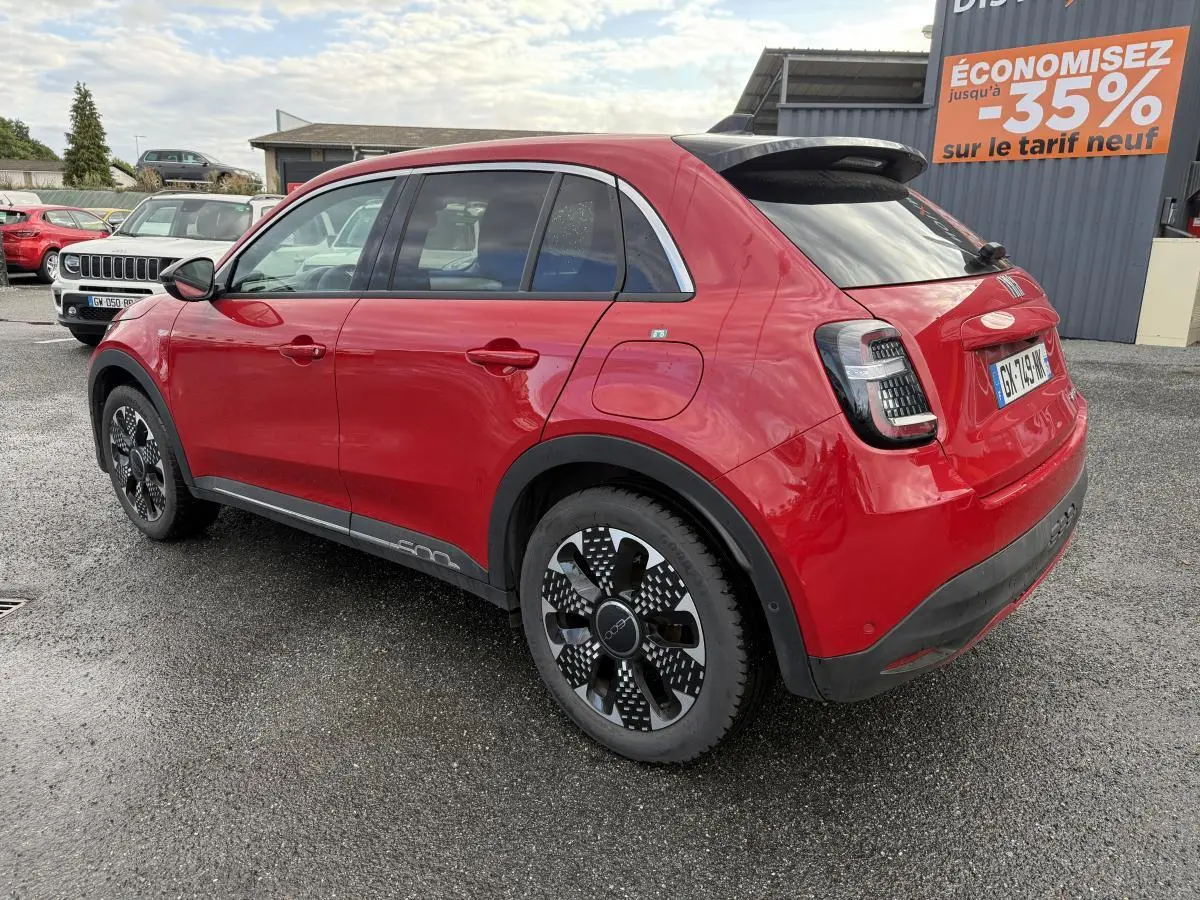 Vue 3/4 arrière droite d'une FIAT 600 La Prima rouge avec jantes alliage 18'' diamantées et antenne requin noir brillant.