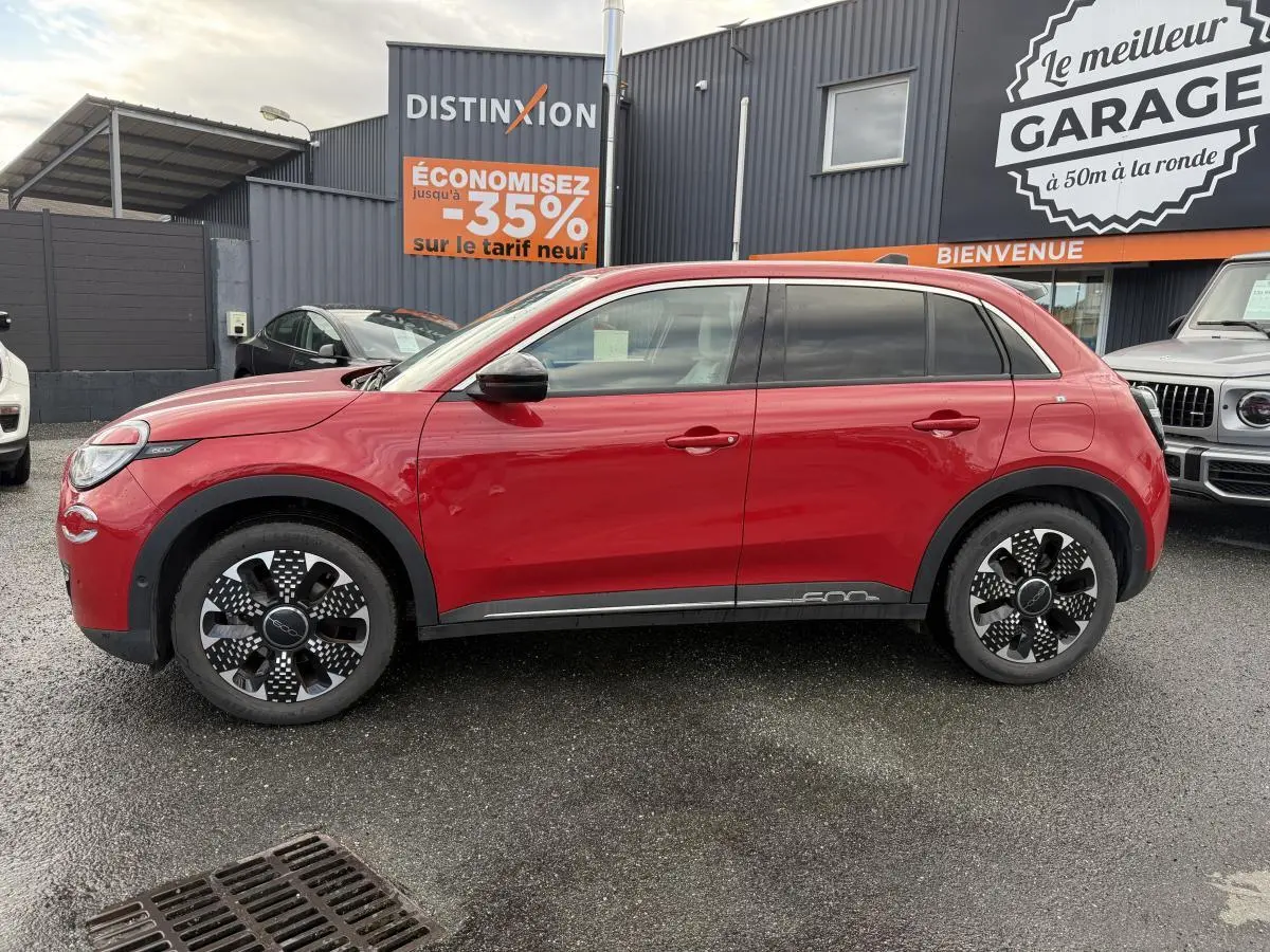 Profil côté gauche d'une FIAT 600 1.2 Hybrid rouge avec jantes alliage 18'' diamantées et vitres surteintées.