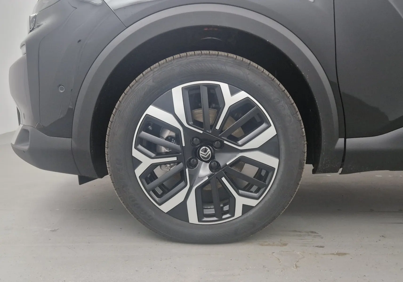 Gros plan sur la roue avant gauche noire d'une Citroën C4 2025, mettant en valeur la jante alu bicolore au design moderne.