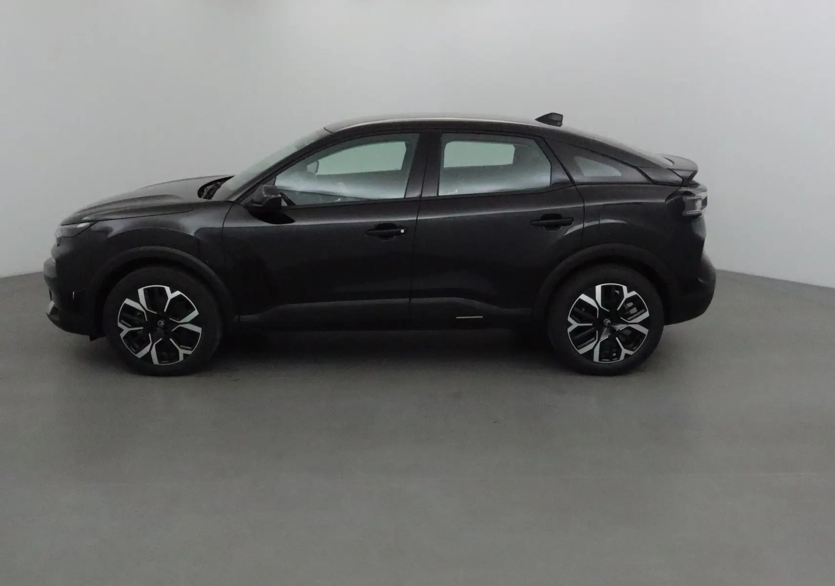 Profil côté gauche d'une Citroën C4 noire 2025, avec jantes alliage noires et détails modernes sur un fond neutre.