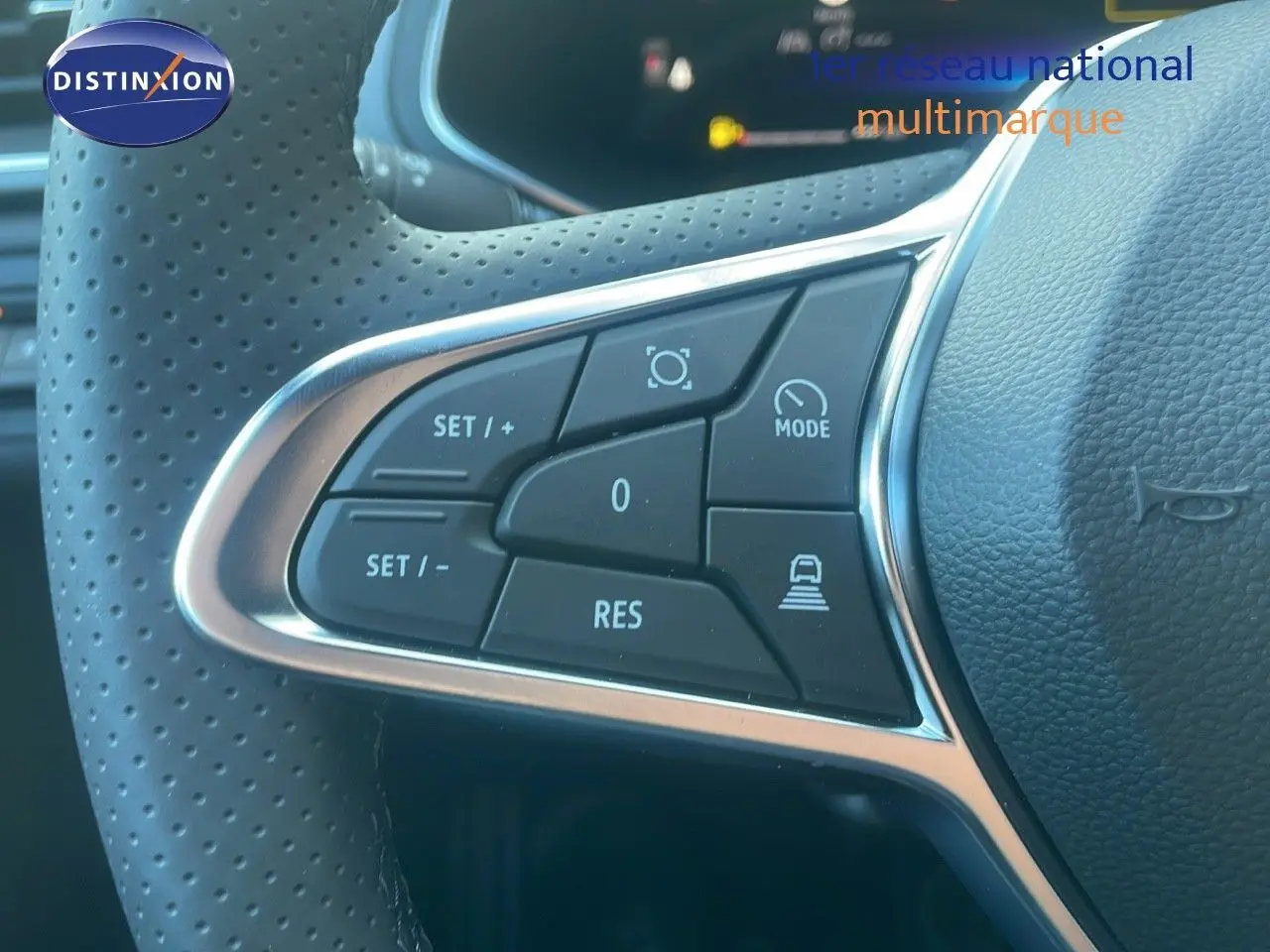 Gros plan sur les commandes du volant perforé noir du Renault Captur E-Tech Hybrid 2025, avec boutons de régulateur et mode.