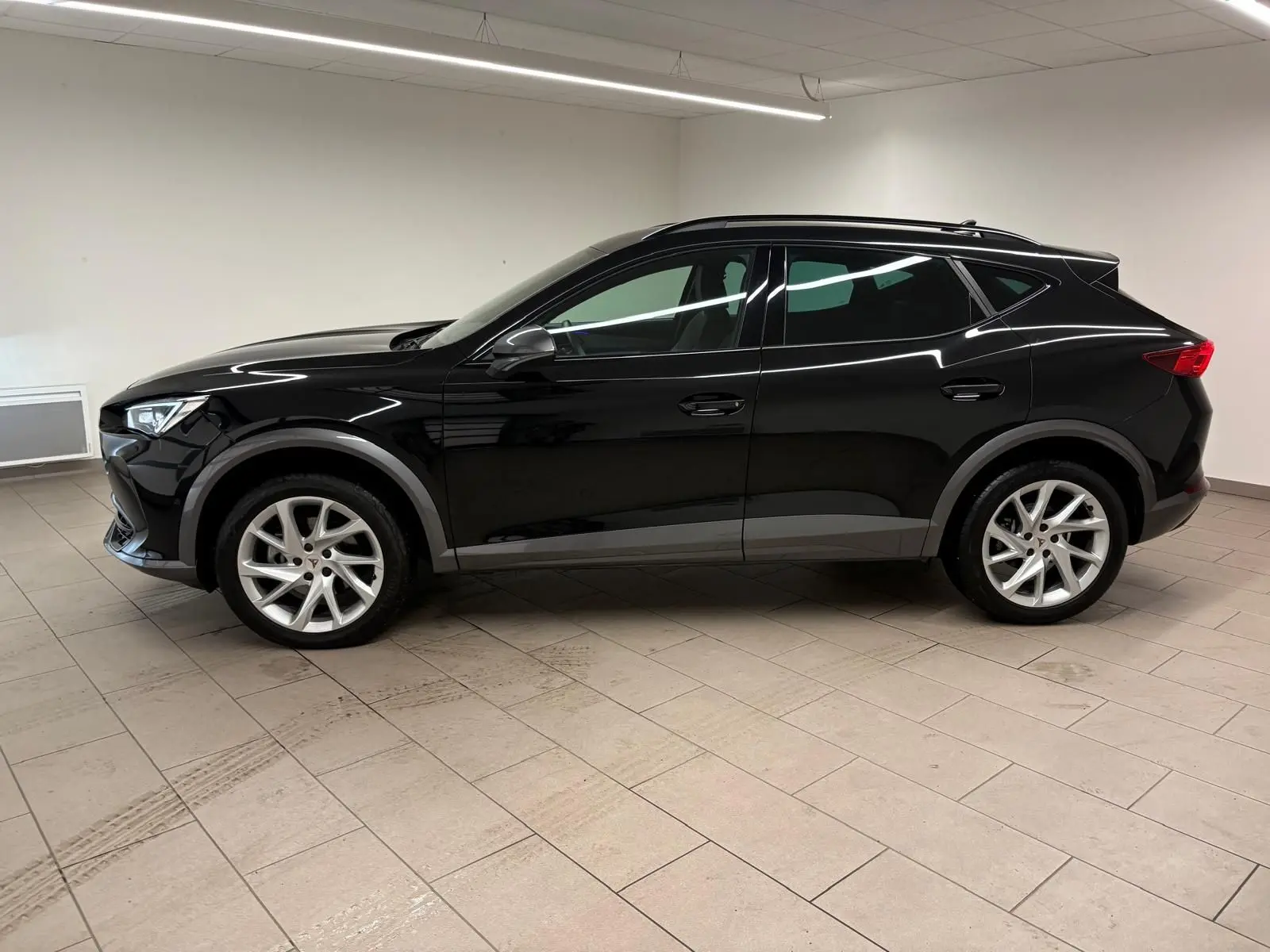 Profil côté gauche d'un CUPRA Formentor 1.5 TSI noir minuit 2024, avec jantes argentées et lignes dynamiques marquées.