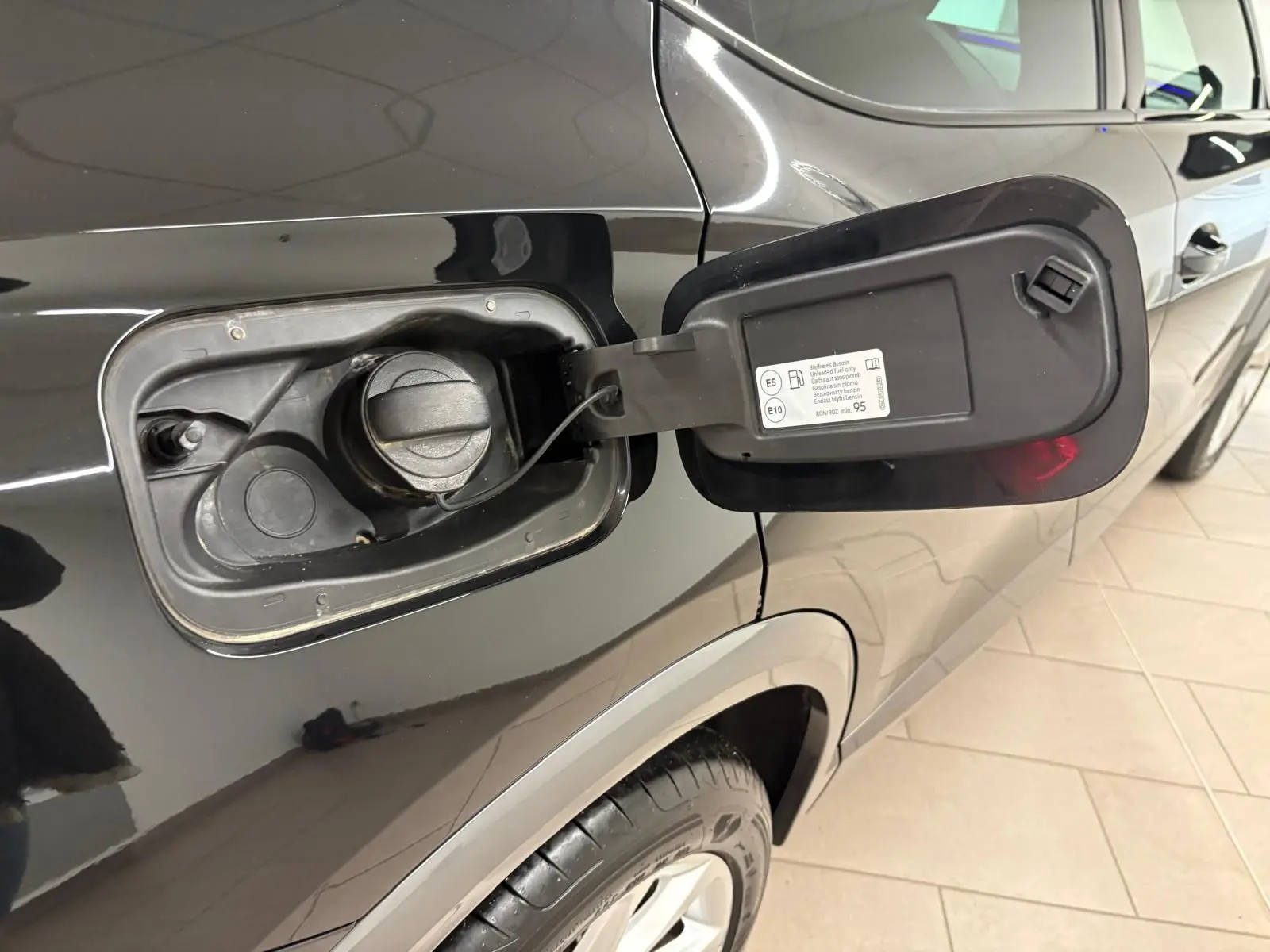 Gros plan sur la trappe à carburant ouverte côté gauche d’un CUPRA Formentor noir minuit, avec bouchon essence visible.