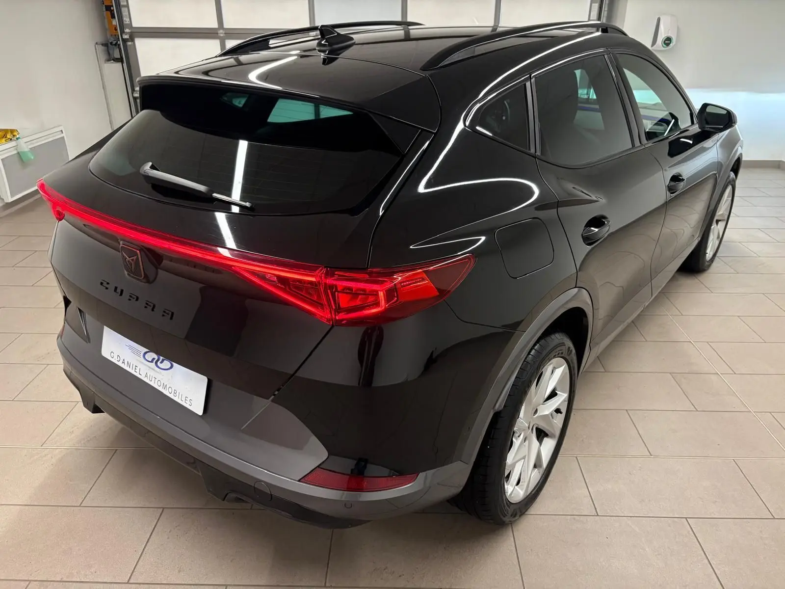 Vue 3/4 arrière droite du CUPRA Formentor 1.5 TSI 150 DSG7 noir minuit avec feux arrière continus et toit panoramique.