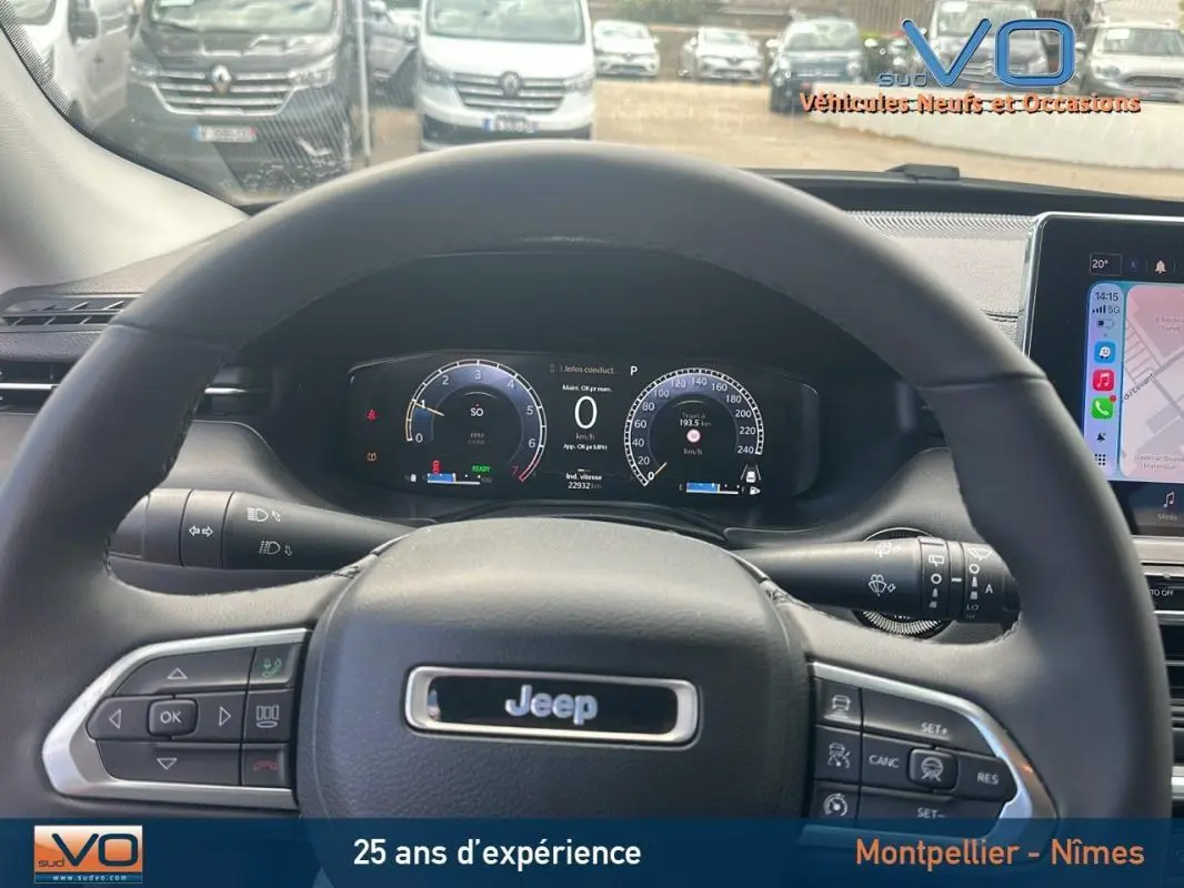 Vue intérieure centrée sur le volant noir d’un Jeep Compass 2023 avec tableau de bord numérique et écran tactile visible à droite.