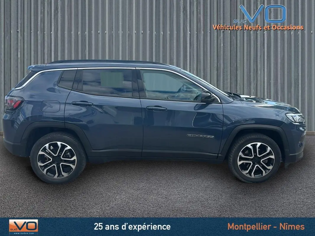 Vue latérale droite d'un Jeep Compass bleu 2023 avec jantes 18 pouces et barres de toit visibles.