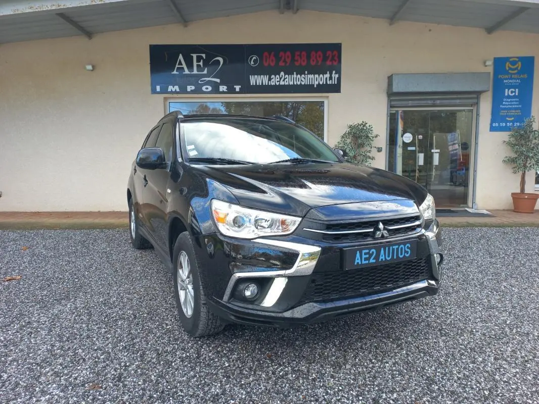 Mitsubishi ASX noir en 3/4 avant droit, avec calandre chromée et jantes 16 pouces visible sur parking gravillonné.