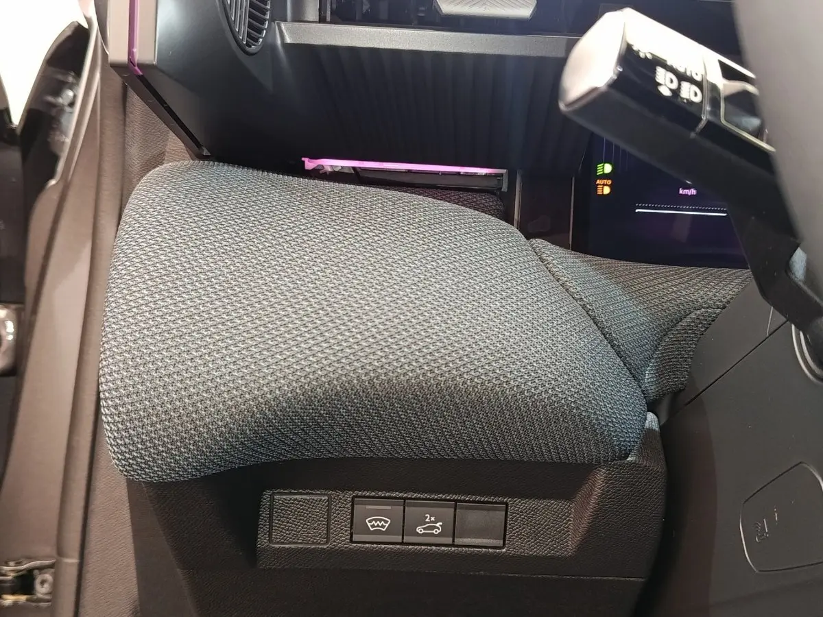 Détail de l'accoudoir central gris et des commandes sous le tableau de bord d'une Citroën C5 hybride 2026.