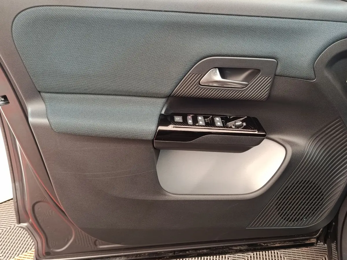 Détail de la porte avant gauche de la Citroën C5 hybride gris foncé, avec commandes de vitres et poignée intérieure.