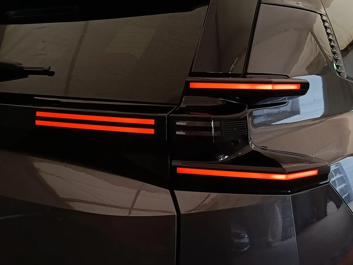 Gros plan sur le feu arrière droit rouge lumineux d'une Citroën C5 hybride gris foncé, finition 2026.