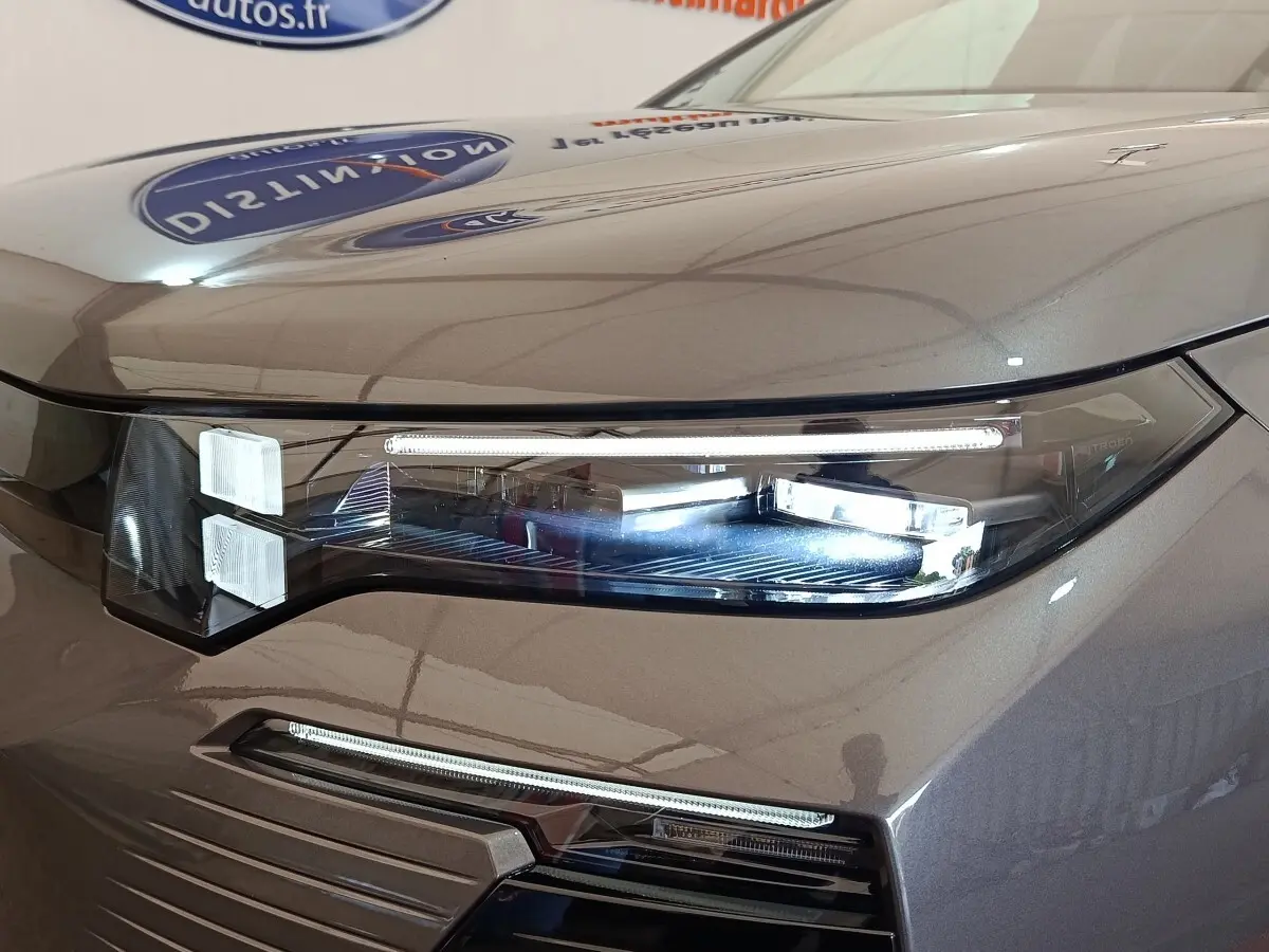 Gros plan sur le phare avant droit gris foncé du Citroën C5 Hybride 2026 avec éclairage LED distinctif.